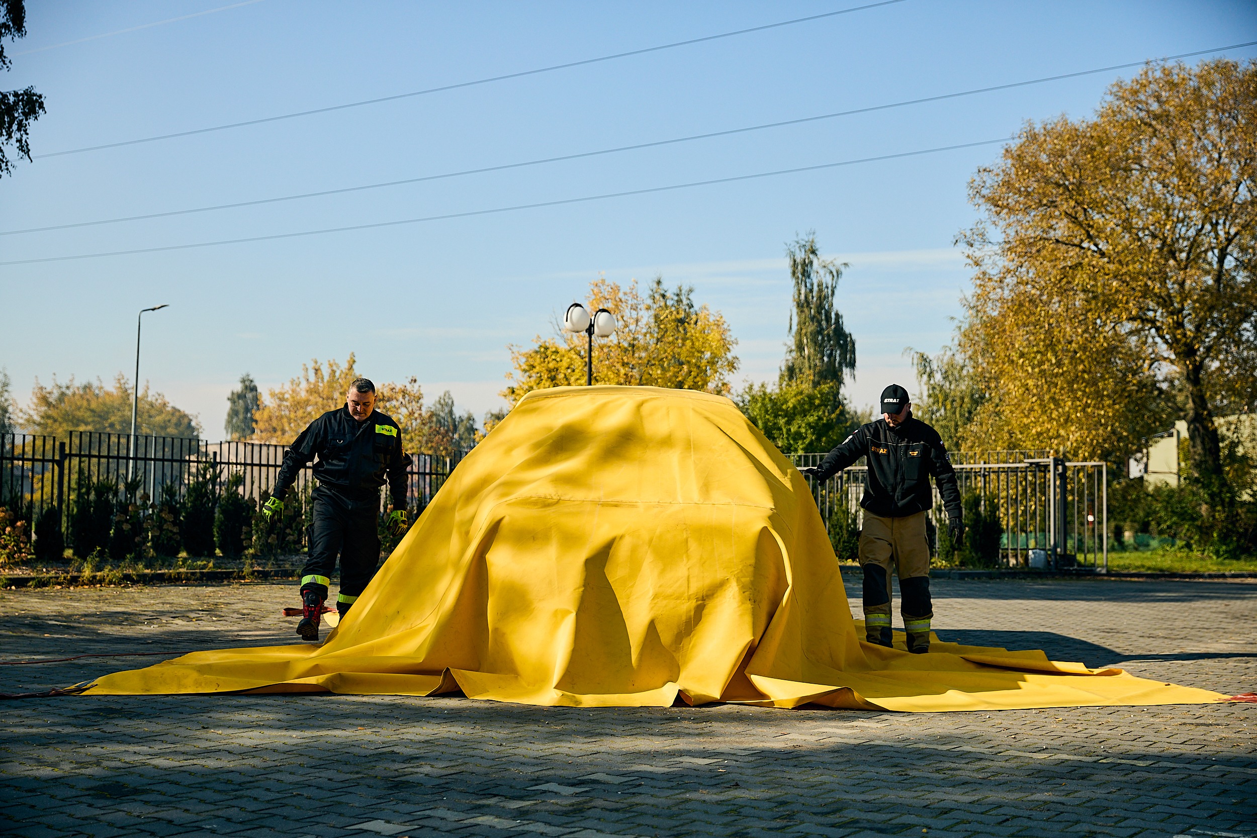 strażacy podczas ćwiczeń z użycia płachty gaśniczej do pojazdów elektrycznych